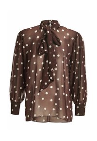 Blouse longue marron transparente à pois blancs, nœud noué au col, épaules bouffantes et poignets boutonnés.