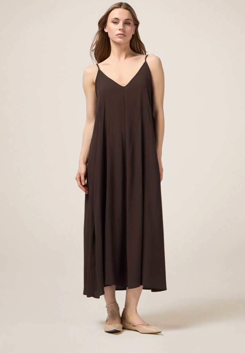 Braunes Maxikleid mit V-Ausschnitt und dünnen Trägern, aus leichtem Stoff für eine fließende Silhouette, kombiniert mit beigen Ballerinas.