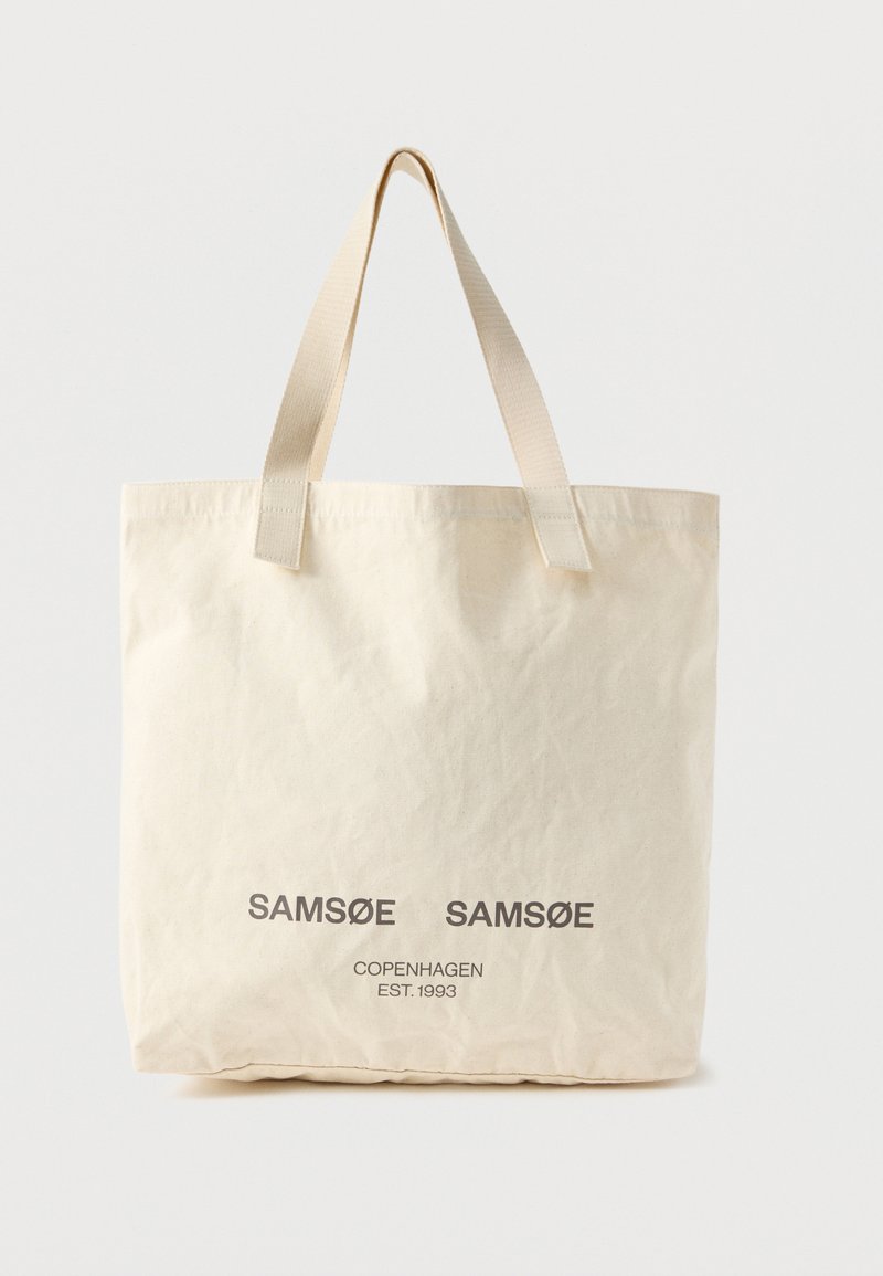 Μπεζ τσάντα ώμου με δύο λαβές, με εκτυπωμένα μπροστά τα λόγια "SAMSOE SAMSOE" και "COPENHAGEN EST. 1993" σε γκρι.