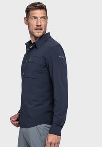 Dunkelblaues Langarmhemd aus leichtem Stoff, mit zwei Vordertaschen und dem auf dem rechten Ärmel gestickten Markennamen.