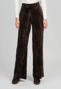 Pantalons larges en velours marron avec des rayures verticales, dotés d'une taille haute, d'une fermeture à bouton et d'une texture lisse et douce.