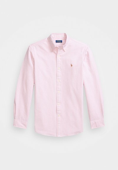 Rozā un baltas svītras ar pogām, apkakli, garām piedurknēm un nelielu izšūtu logo kreisajā krūtī. Kokvilnas materiāls.