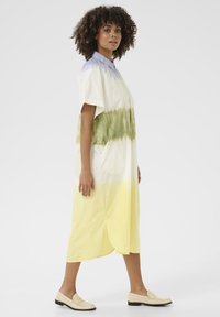 Kaklo trikampiu, trumpų rankovių medvilnės suknelė su ombre raštu: šviesiai violetinė, žalia ir geltona gradientas. Pasižymi išlenktu apačiu ir šoninėmis kišenėmis.