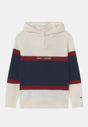 Kremowa dzianinowa bluza z kapturem z granatowo-czerwonymi poziomymi paskami, półzamek z przodu i logo „Tommy Hilfiger” na środku klatki piersiowej.