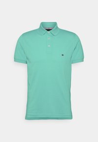 Mintgrön kortärmad polo med tre knappar och en liten Tommy Hilfiger-logotyp på vänster bröst.