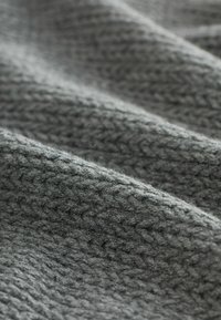 Texturovaná tmavošedá látka s tkaným vzorem, která ukazuje měkký, chlupatý povrch a jemné vlny v materiálu.
