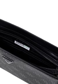 Schwarzes Portemonnaie mit strukturierter grauer Außenseite und Reißverschlussfach. Verziert mit einem GUESS-Label und einem dreieckigen Logo-Akzent.