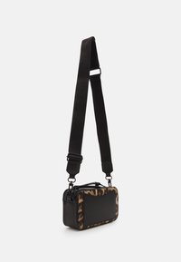 Black and leopard print crossbody bag, rectangular shape, soft textured fabric, adjustable strap, zip closure, with a front pocket.