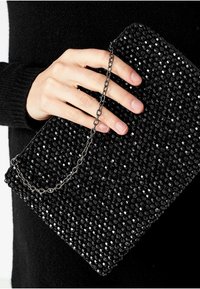 Svart pärlclutch med kedjeträdrag, med ett hexagonalt pärlmönster, texturerad yta och rektangulär form. Handhållen.