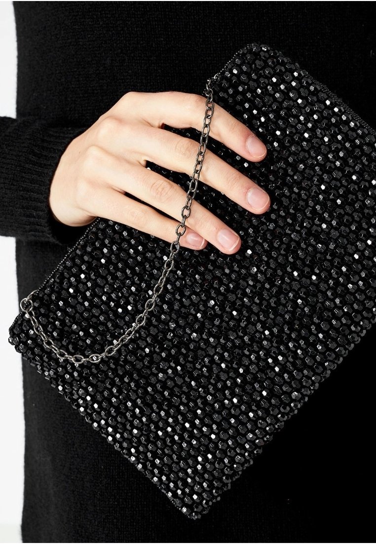 Svart pärlclutch med kedjeträdrag, med ett hexagonalt pärlmönster, texturerad yta och rektangulär form. Handhållen.