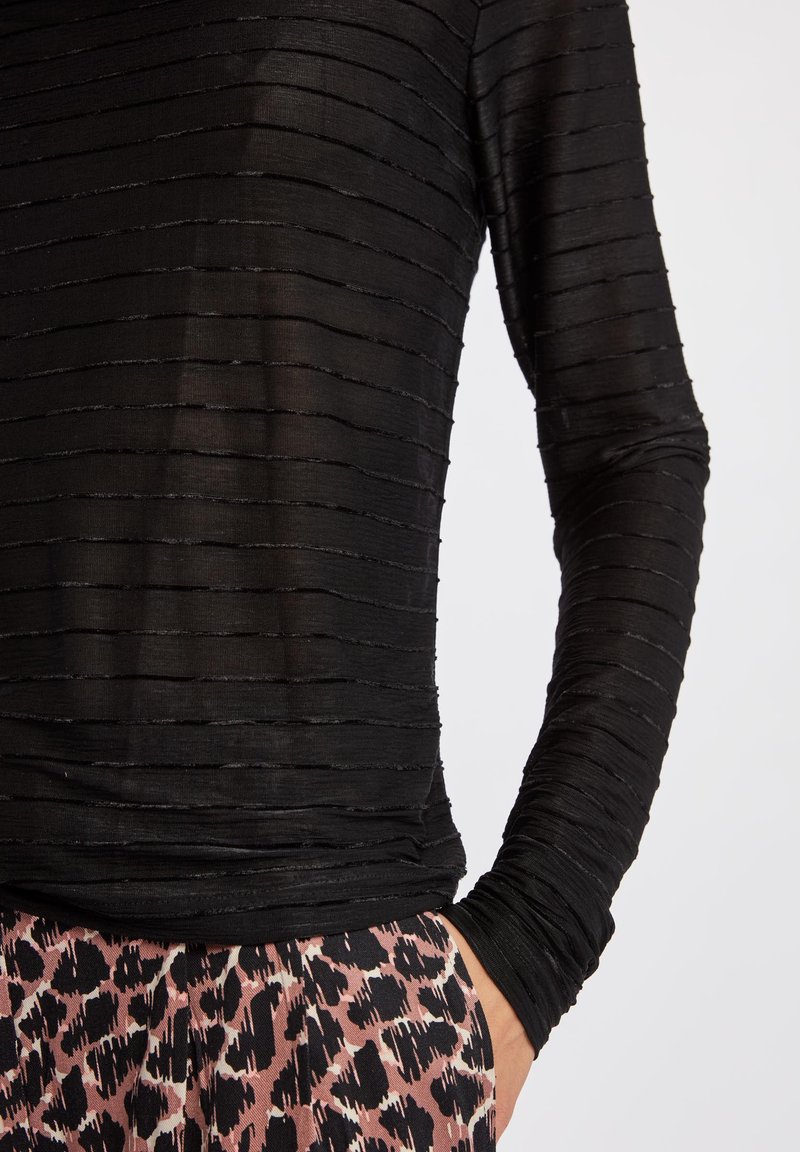 Schwarzes Langarmshirt mit einem strukturierten, gestreiften Muster. Der Stoff ist durchsichtig und hat eng anliegende Ärmel sowie einen runden Ausschnitt.