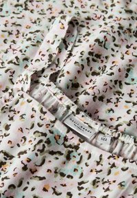 Lekki bawełniany materiał z pastelowym różowym tłem i rozrzuconym wzorem lamparta w odcieniach zieleni, czerni i delikatnego niebieskiego. Widoczna metka.