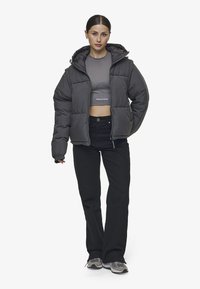 Grå puffjacka med huva, med en quiltad design, som är kombinerad med en tight grå topp och svarta vida byxor. Texturerade sportiga sneakers.