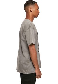 Gray oversized t-shirt with short sleeves, featuring a faded texture and graphic print on the front. Straight cut hem, casual fit.