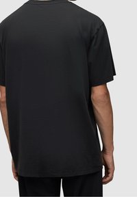 Czarny bawełniany t-shirt o luźnym kroju. Posiada krótkie rękawy, okrągły dekolt i gładką fakturę z minimalnymi detalami.