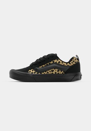Sneaker nera con pannello laterale in stampa leopardata, materiale testurizzato, suola piatta in gomma e design a punta arrotondata. Presenta lacci neri e una linguetta sul retro.