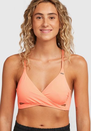 Haut de soutien-gorge couleur pêche avec un design triangulaire et un style enveloppant, doté de fines bretelles et de découpes sur les côtés.