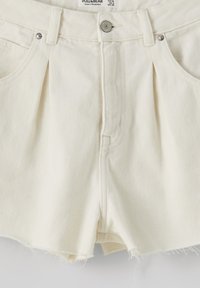 Bílé denimové šortky s vysokým pasem, s předními sklady, dvěma kapsami a třepeným lemem. Obsahují kovový knoflík a nýtky.