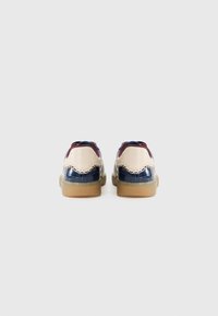 Brune og blå lærersneakers med strukturert overdel, kremfargede detaljer og beige gummisåler. Sømdetaljer rundt hælområdet.
