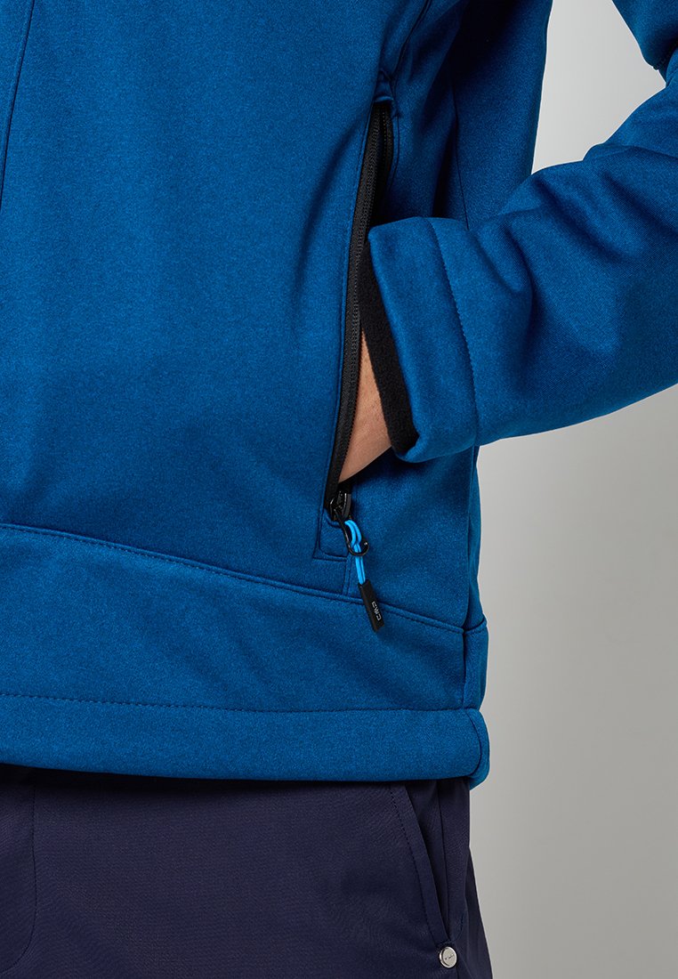 Chaqueta de forro polar azul con un bolsillo en el pecho con cremallera y forro negro. Las características incluyen un cordón ajustable y un tirador de cremallera en contraste.