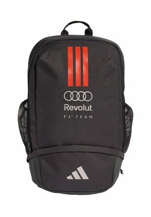 Černý batoh s červenými vertikálními pruhy, logy Revolut a Audi, textem "F1 Team" a logem Adidas na přední kapse. Boční síťované kapsy.