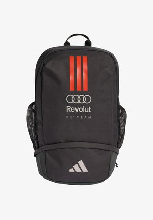 Sac à dos noir avec des rayures verticales rouges, les logos Revolut et Audi, le texte "F1 Team" et le logo Adidas sur la poche avant. Poches latérales en maille.
