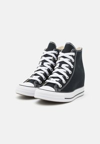 Svarta canvas hög-top sneakers med vita snören, gummitåhätta och kilklack. Har kontrasterande vitt sömnad och ränder på sulan.