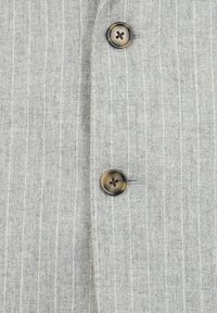 Tessuto grigio a righe sottili con finitura testurizzata, caratterizzato da due bottoni scuri sul fronte di un blazer. Design pulito con linee verticali.