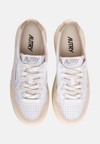 Sneaker bianche con una tomaia in pelle e camoscio testurizzati, accenti crema, punta rotonda, dettagli perforati e lacci tono su tono. Marchio "AUTRY" visibile.