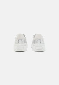Srebrne sneakersy z metalicznym wykończeniem, białą gumową podeszwą i zamszowymi akcentami na pięcie. Posiadają wyściełany kołnierz i subtelne logo.