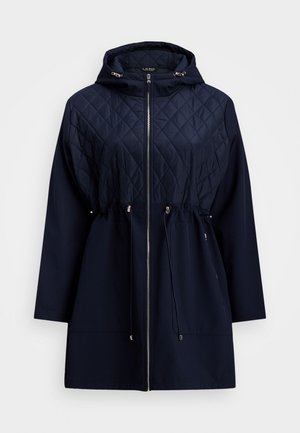 Veste à capuche en bleu marine, matelassée, avec une taille à cordon, fermeture éclair à l'avant et manches longues. Fabriquée en tissu lisse, avec un motif en losanges sur le dessus.