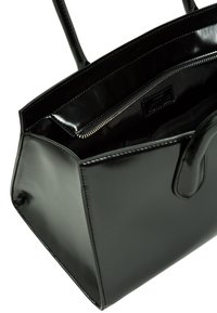 Borsa a mano in pelle verniciata nera con una forma strutturata, due manici e tasca interna con zip, caratterizzata da una finitura liscia e cuciture sottili.