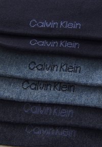Calzini Calvin Klein in blu scuro e grigio, che mostrano una morbida texture a maglia. Ogni paio presenta il nome del marchio ricamato in contrasto.