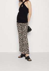 Svart halterneck topp med nyckelhålsdetalj, i kombination med bruna och svarta leopardmönstrade byxor med utsvängd ben, och svarta klackmules. Accessoarer med en svart väska.