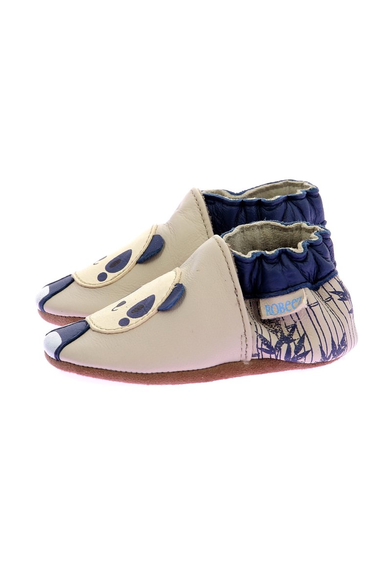 Chaussures en cuir beige avec un design de panda ; col élastique navy ; semelle texturée couleur tan ; bout arrondi ; accents décoratifs représentant un visage.