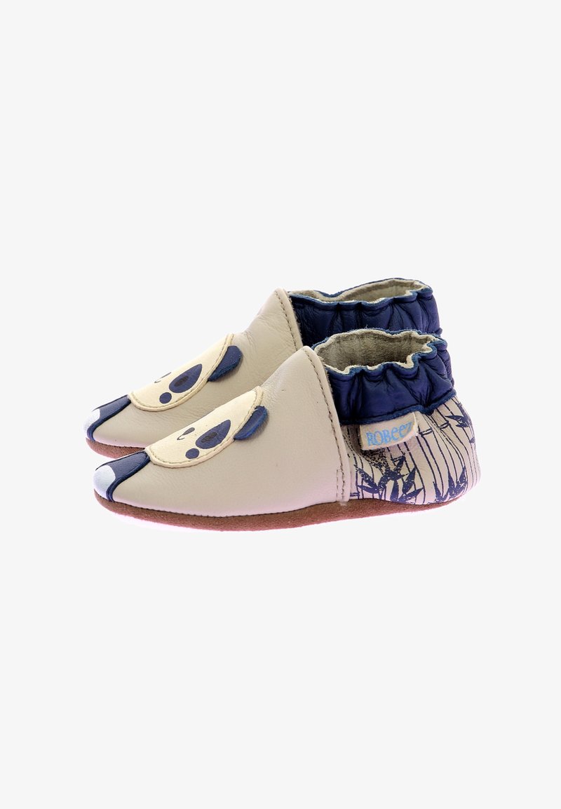 Chaussures en cuir beige avec un design de panda ; col élastique navy ; semelle texturée couleur tan ; bout arrondi ; accents décoratifs représentant un visage.