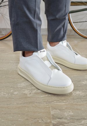 Sneakers bianchi in pelle con design slip-on, presenti un finish testurizzato, una banda elastica e suola in gomma color crema. Marchio sul tallone.