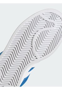 Sola de borracha branca com padrão zigzag, parte superior em camurça azul, apresentando uma faixa branca de destaque na lateral. A textura é suave com um design em relevo.