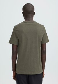 Pamucna majica maslinasto zelene boje s kratkim rukavima i okruglim izrezom. Jednostavan dizajn s glatkom teksturom i ravnim rubom.