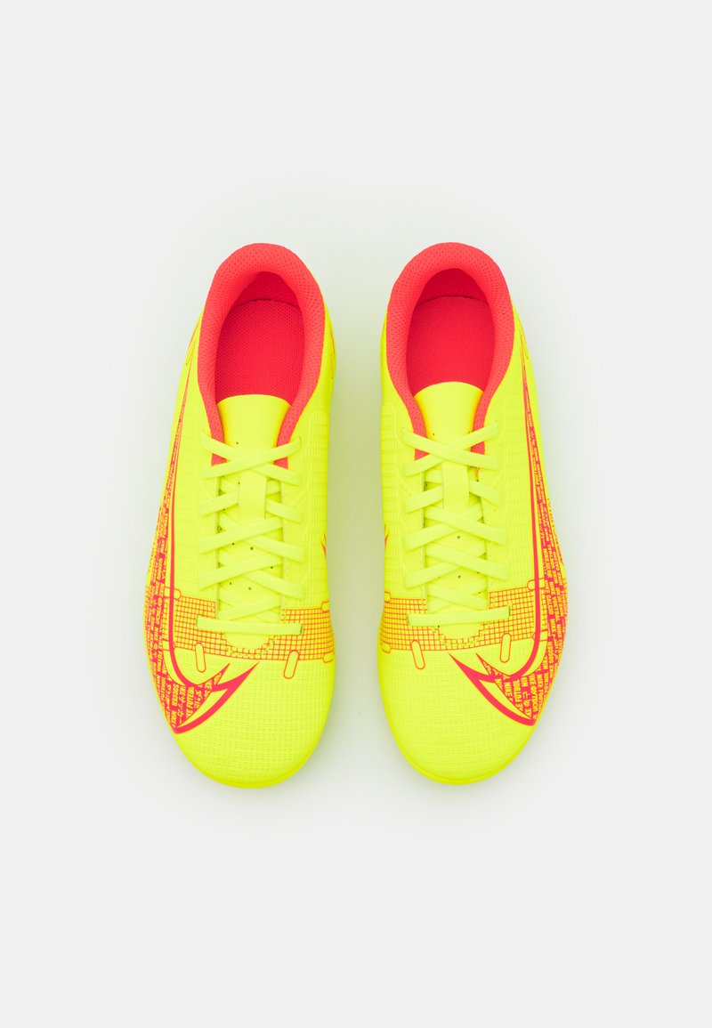 Des crampons de football jaunes vifs avec des accents roses, dotés d'une tige texturée, d'un système de laçage et d'un motif graphique sur le côté.