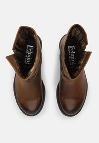 Bottines en cuir marron avec un bout rond, des coutures décoratives et une doublure en tissu rayé coloré. Design à enfiler avec des accents latéraux.
