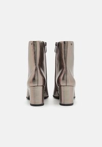 Botines metálicos con un diseño elegante, que presentan una punta cuadrada, tacón bloque y cremallera lateral, exhibiendo una superficie lisa y brillante.