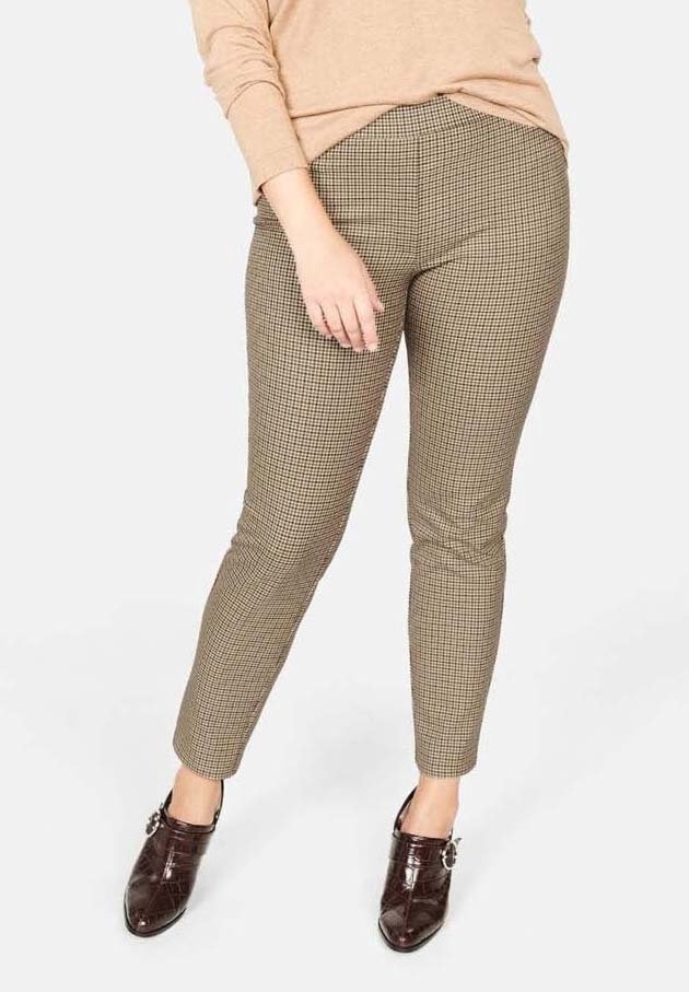 Pantaloni slim-fit a quadretti marroni e crema, realizzati in tessuto intrecciato. Presentano una vita elastica e una silhouette aderente. Indossati con scarpe marroni scure.