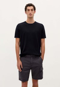 Czarny t-shirt z krótkim rękawem w połączeniu z ciemnoszarymi szortami cargo z bocznymi kieszeniami i nieco luźniejszym krojem. Prosty wzór, materiał mieszany z bawełny.