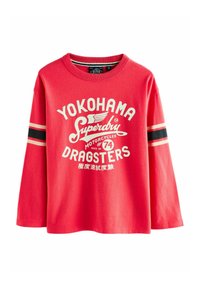 Röd långärmad skjorta i bomull med ett grafiskt tryck som visar "YOKOHAMA SUPERDRY DRAGSTERS" i vitt, med svarta och beige ränder på ärmarna.
