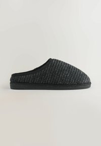 Zwarte geweven stoffen slipper met een ronde neus, gestructureerde bovenkant en een contrasterende zwarte rubberen zool. Lichtgevend gestoffeerd rond de opening.