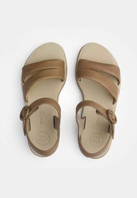 Rudos odinės šlepetės su dviem kryžminėmis juostelėmis, apvaliu sagties detalėmis ir paminkštintu smėlio spalvos padu, pažymėtu "SUPER SOFT". Plokščias padas.