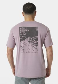 Camiseta de color púrpura claro con un gráfico de montaña y texto en la parte de atrás. Mangas cortas, cuello redondo, fabricada con tejido transpirable.