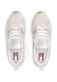 Light beige sneakers with silver accents, mesh upper, white laces, and rubber sole. Features logo on tongue and back pull tab.