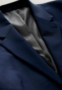 Marineblauwe blazer met een gladde satijnen voering, voorzien van een notch-kraag en een enkele borstzak, die een tailormade ontwerp en strakke lijnen onderstrepen.